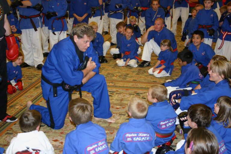Black Belt instructor kneeling to talk with young students in blue Mile High Karate uniforms at the 2007 Champion's Reunion