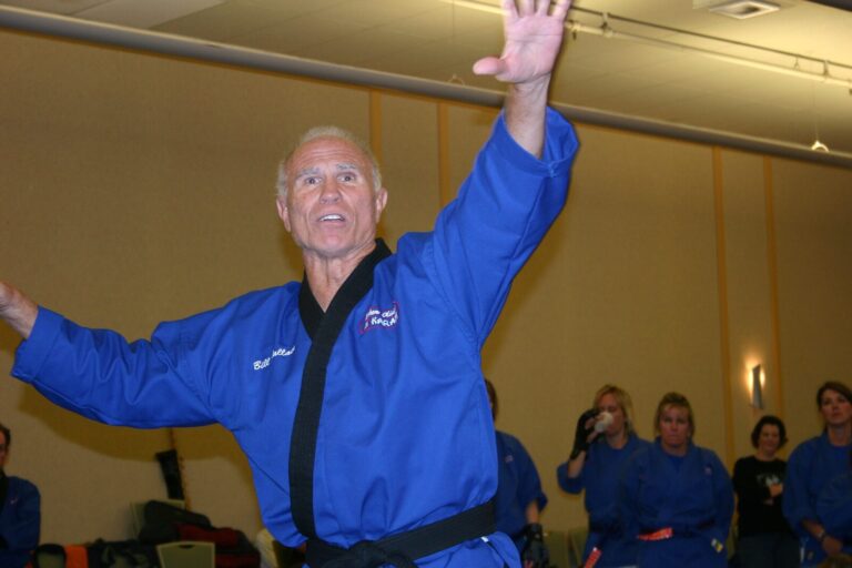Bill Wallace, his name embroidered on his blue uniform, raising his arm high while teaching at the 2007 Champion's Reunion