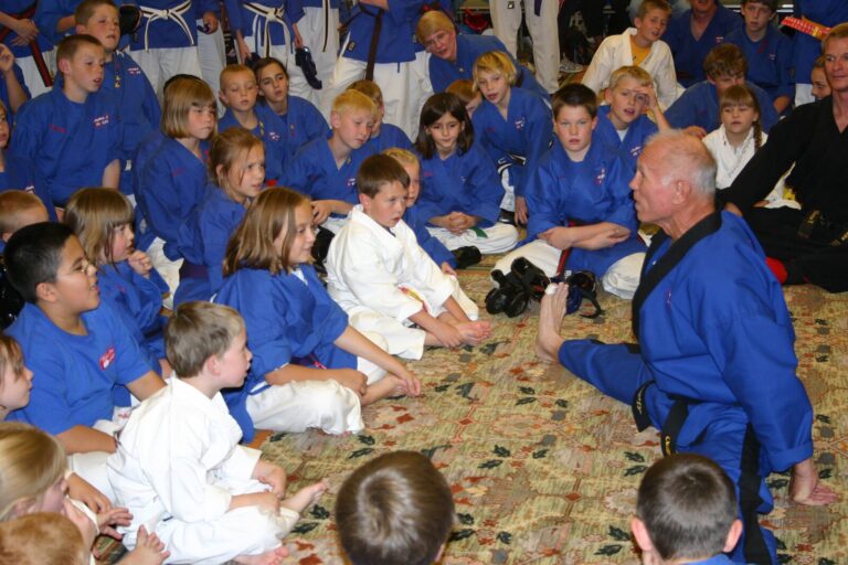 Black Belt instructor seated on the floor talking with young students at the 2007 Champion's Reunion