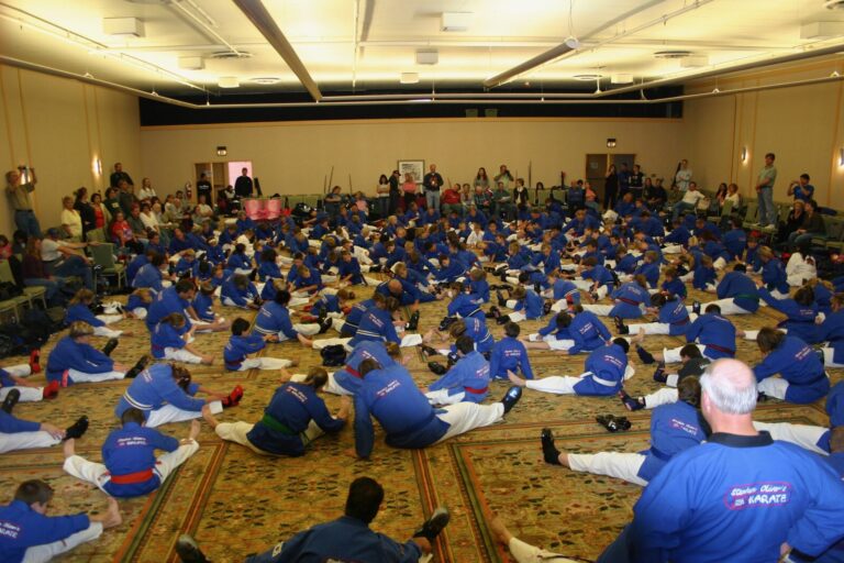 Wide view of a hotel ballroom filled with students in blue uniforms stretching on the floor at the 2007 Mile High Karate Black Belt Retreat