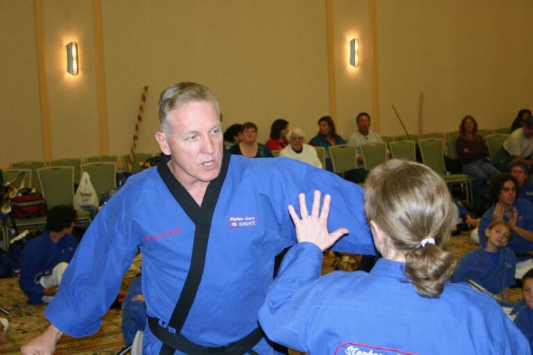 Black Belt instructor in a blue uniform coaching a student through a self-defense technique at the 2007 Champion's Reunion