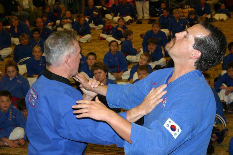 Two Black Belts demonstrating a choke defense in front of seated students at the 2007 Champion's Reunion